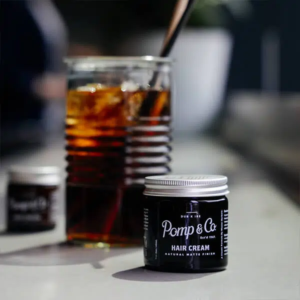 God hårvoks fra Pomp & Co. Hair Cream fra Pomp & Co. med drink i baggrunden.