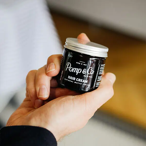Hair Cream hårvoks Ung fyr holder hårvoks fra Pomp & Co. i hånden.