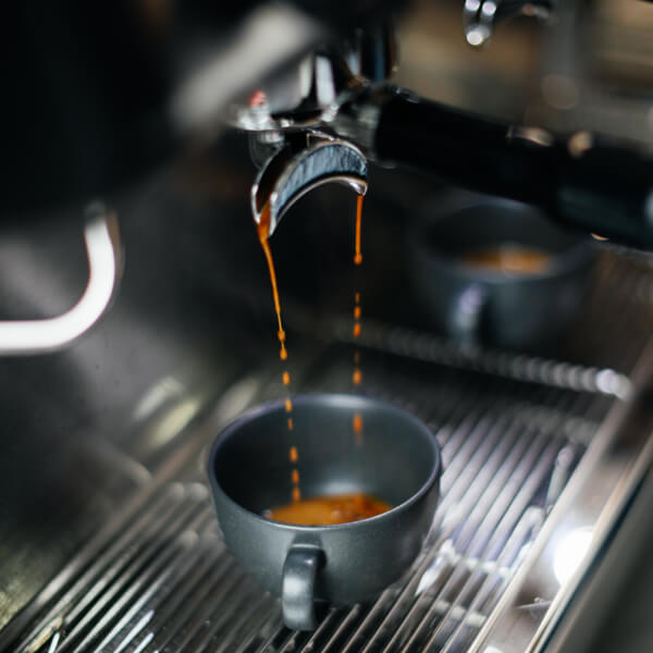 Kaffe brygges Lækker kaffe brygges på stor espressomaskine i barbershop.