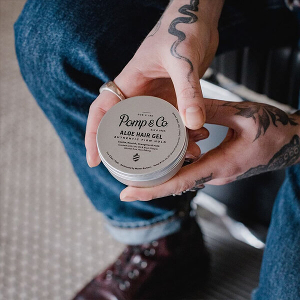 Klassisk hårgelé fra Pomp & Co Ung mand i mørkeblå jeans holder hårgelé fra Pomp & Co. i hånden.