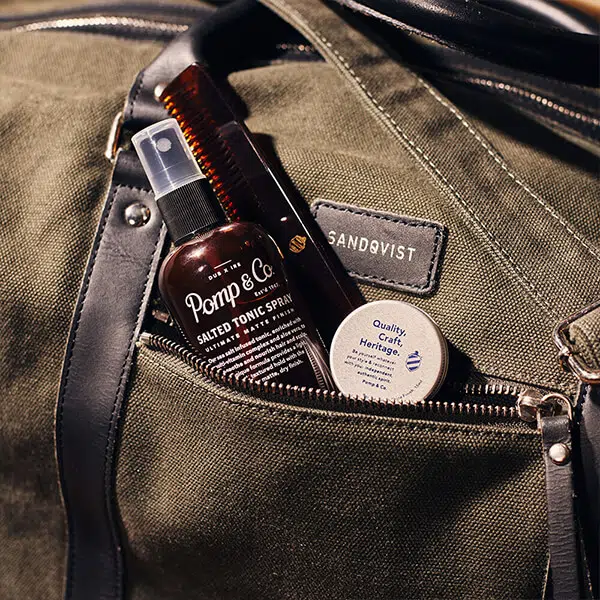 Taske med Pomp & Co. produkter Pomp & Co. produkter til farten i et rum på en taske.